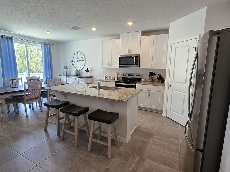 Open-concept kitchen with granite island seating, stainless appliances, and an adjacent dining area by sliding doors.