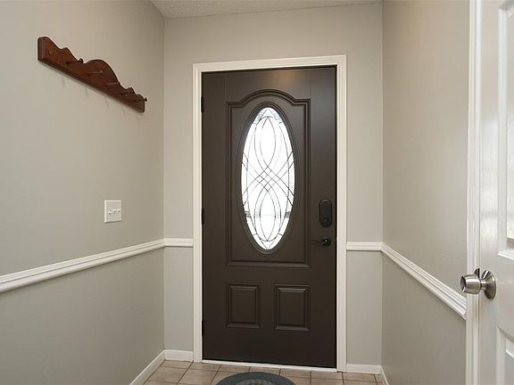Welcome home! This beautiful entrance features a bright front foyer, dark stained front door with glass detailing for natural light, stunning tile floors, and chair rail.