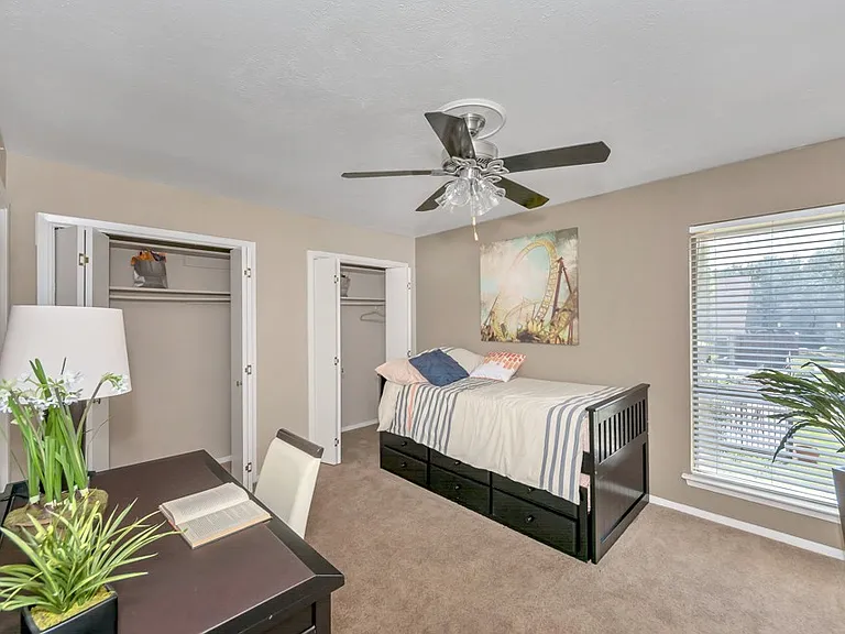 Spacious bedroom with ceiling fan, large window for natural light, and walk-in closet at Watersong Villas Apartments in North Dallas.