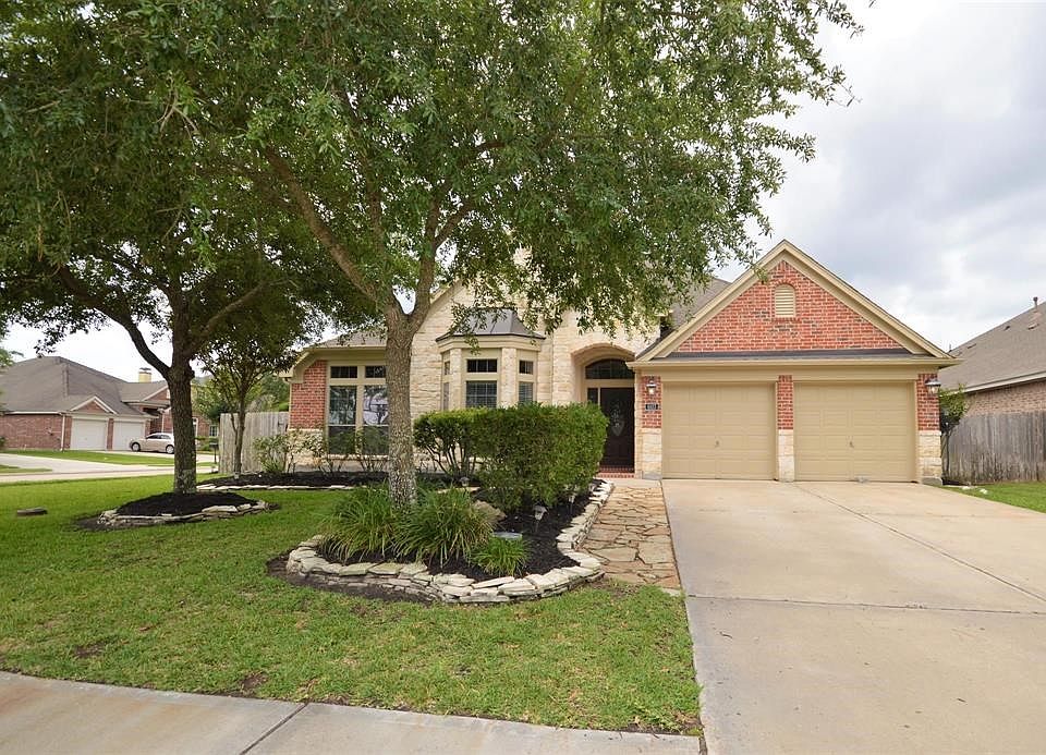 Beautiful entry bordered with manicured landscaping and live oaks.