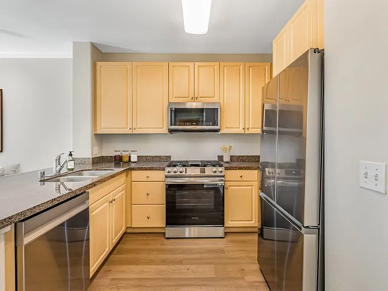 Classic Package II kitchen with with oak cabinetry, dark granite countertops, stainless steel appliances, and hard surface flooring
