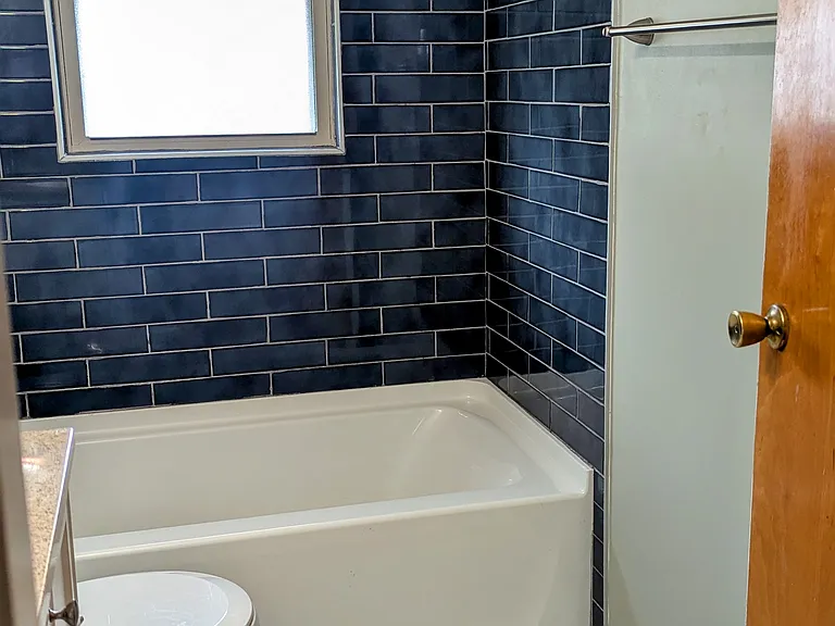 The bathroom offers a tub with shower and an exhaust fan.