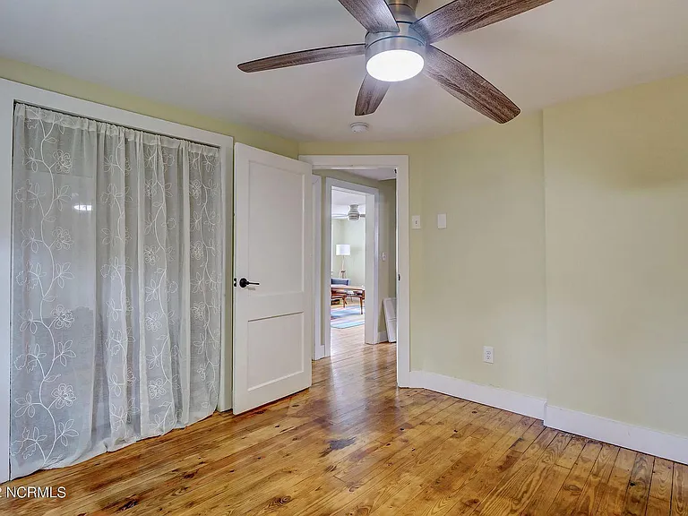 Bedroom 1 with wood floors and remote controlled ceiling fan.
