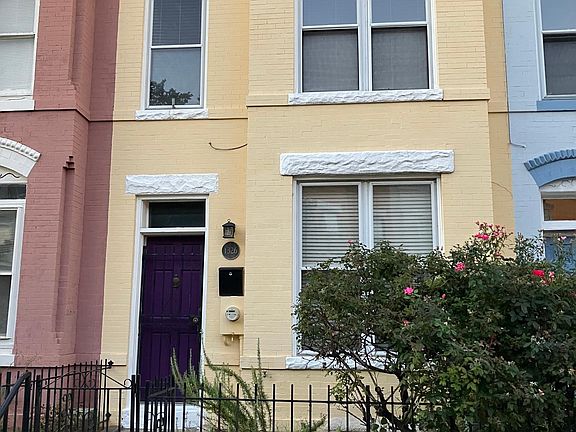 Front of house with garden bench and rose bush.