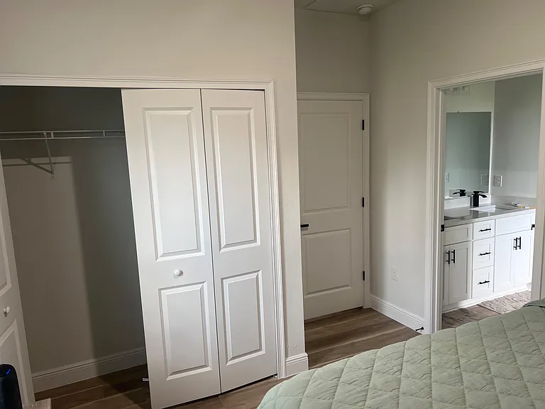 Bedroom area with a sliding-door closet and convenient access to a bathroom vanity with ample cabinet storage.