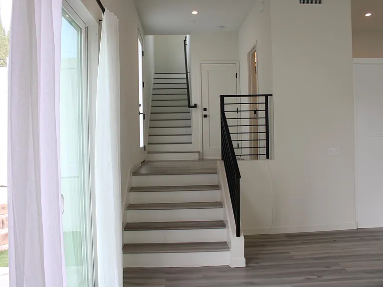 from living room floor looking up to the stairs and landing half ba to the right and front door on the left. Back is the door to the garage.