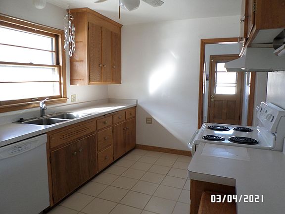 Photo of kitchen taken from dining room doorway. Main entry door on north end of the house leads in to the kitchen.