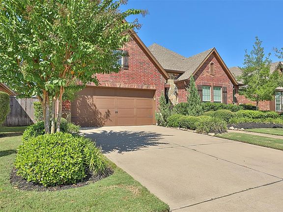 View of trees, vegetation and double wide driveway leading to the 2 car garage.