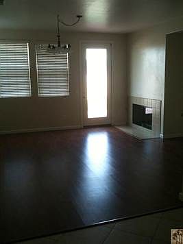 Family room off the kitchen with fireplace and access to the large backyard. The flooring is a laminate. All windows have blinds.