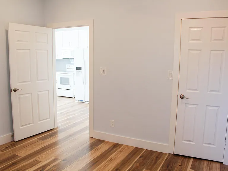 View of bedroom looking out into your kitchen and bedroom walk-in closet door. Light switch also includes a separate fan switch.