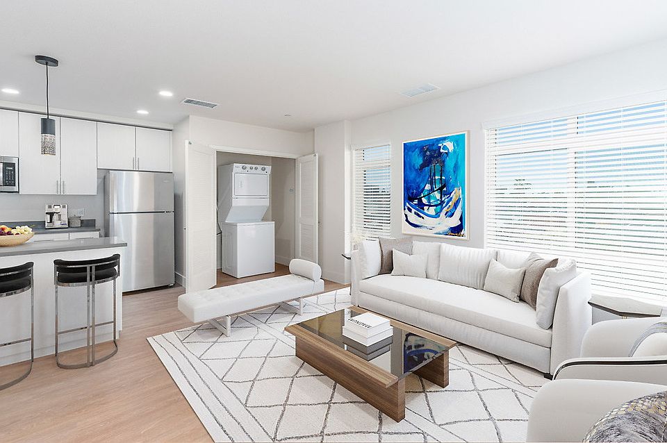 Staged open living room and kitchen with hardwood style flooring and stainless steel appliances. In-home washer and dryer.