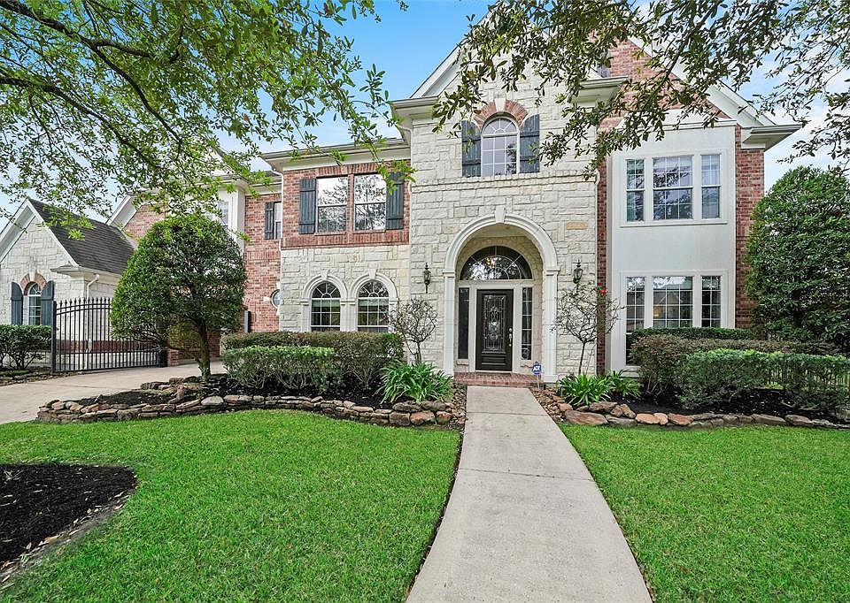 The exterior features brick and stone and a beautiful landscape.