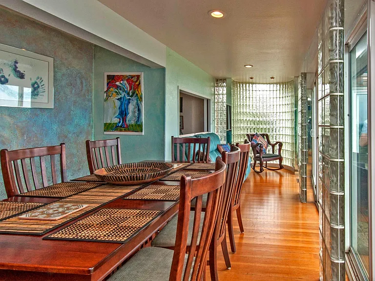 Dining room, glass brick wall, couch beyond table.