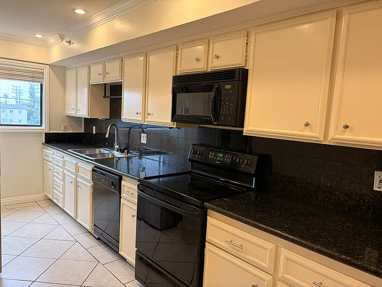 Kitchen with ample cabinet storage, black countertops, and clean appliance setup.