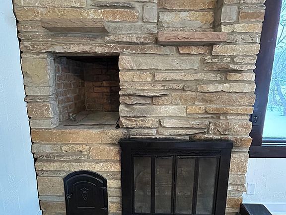 Lannon stone wood burning fireplace with heating blower and wood storage