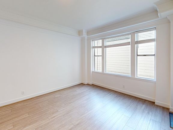 Spacious room with wood-like flooring and a large window offering natural light