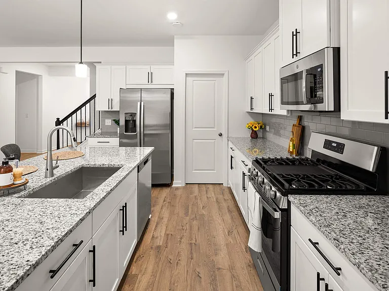 Spacious kitchen with an island, ample storage, stainless steel appliances and view into the living room.
