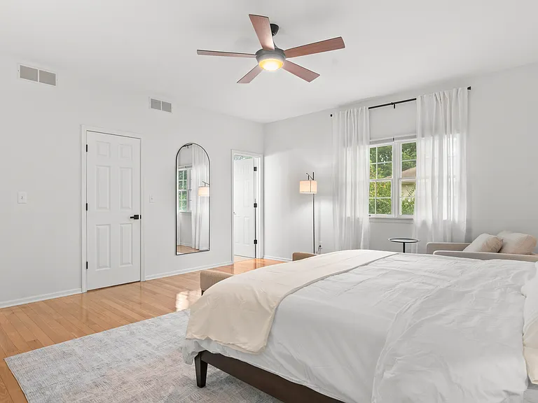 Primary bedroom with a comfortable reading chair, generous closet space, and private ensuite bathroom.