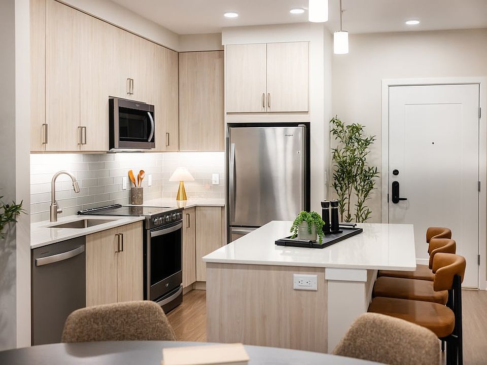 Upgrade Collection kitchen with oak cabinetry, stainless steel appliances, white quartz countertops, light grey tile backsplash, pendant lighting and hard surface flooring