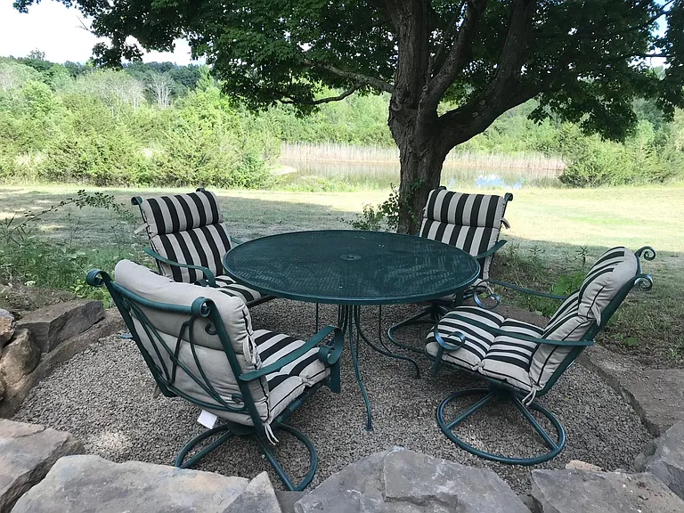 Shaded outdoor sitting area with pond and fields view
