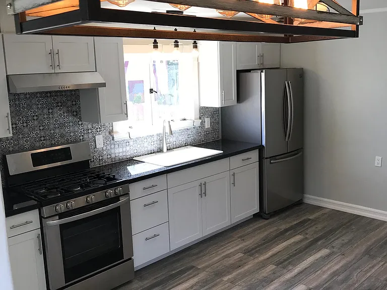 View of the spacious kitchen and dining area with fresh paint, new tile, fixtures, appliances, hardwood flooring, and cabinets.