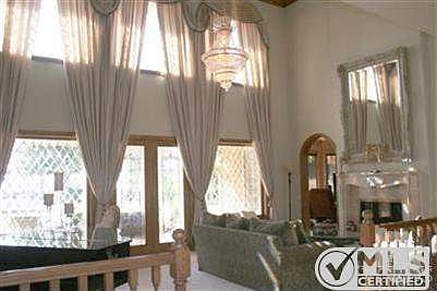 Formal living Room with Fireplace.Leaded glase windows and doors lead to a covered patio that over looks the grounds and pool.