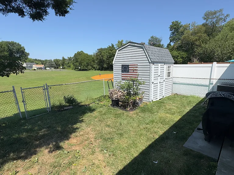 Backyard with fence and shed. Overlooking baseball field and playground.