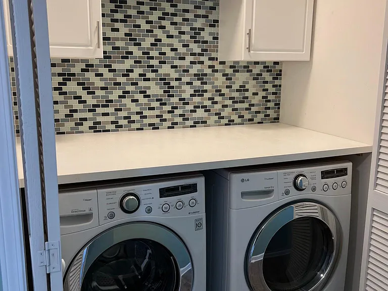 Laundry closet features cabinets, a clothes folding shelf and washer and dryer