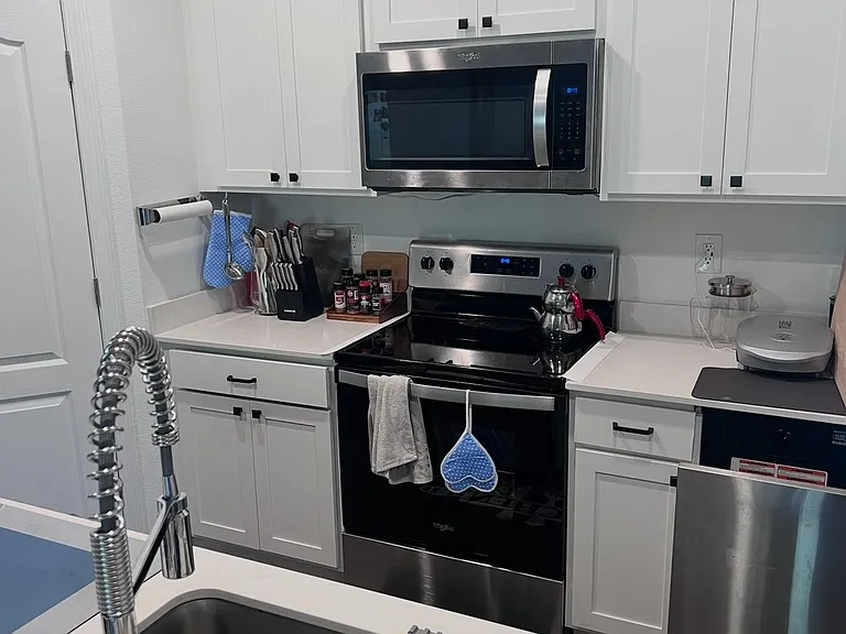 U-shaped kitchen with white shaker cabinetry, quartz-look counters, and stainless steel range, microwave, and dishwasher.