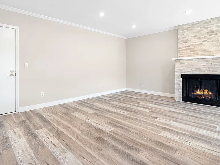 Hardwood floored living room with stone accented fireplace.