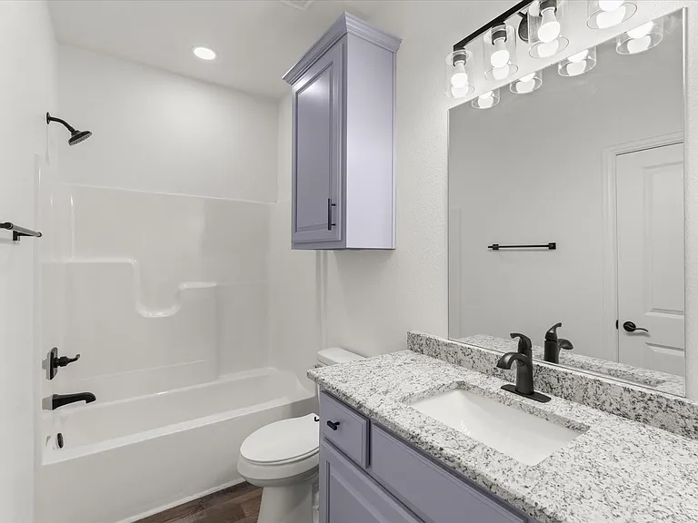 Bathroom featuring a white integrated tub and shower unit with matte black fixtures