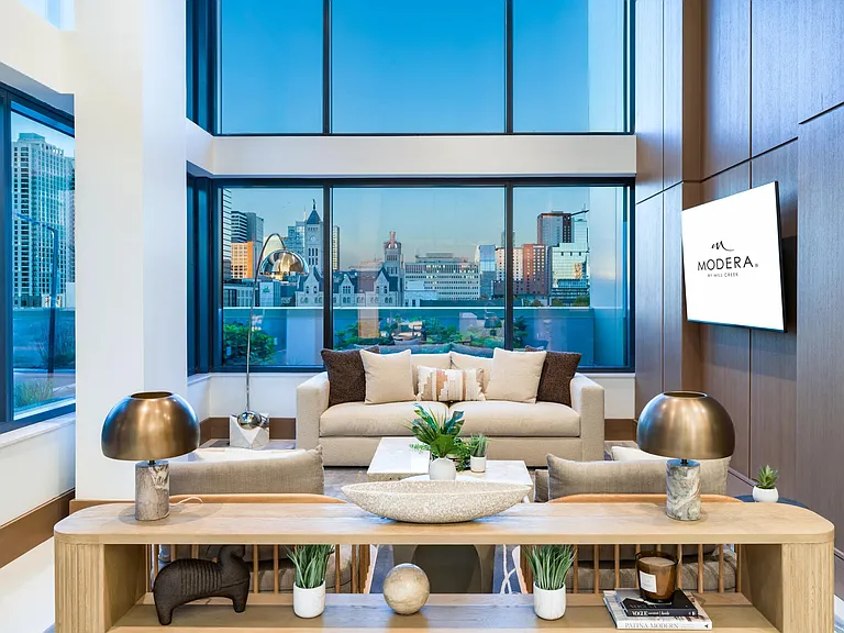 A light-filled resident lounge at Modera McGavock, where expansive windows and refined design create a comfortable place to relax and connect.