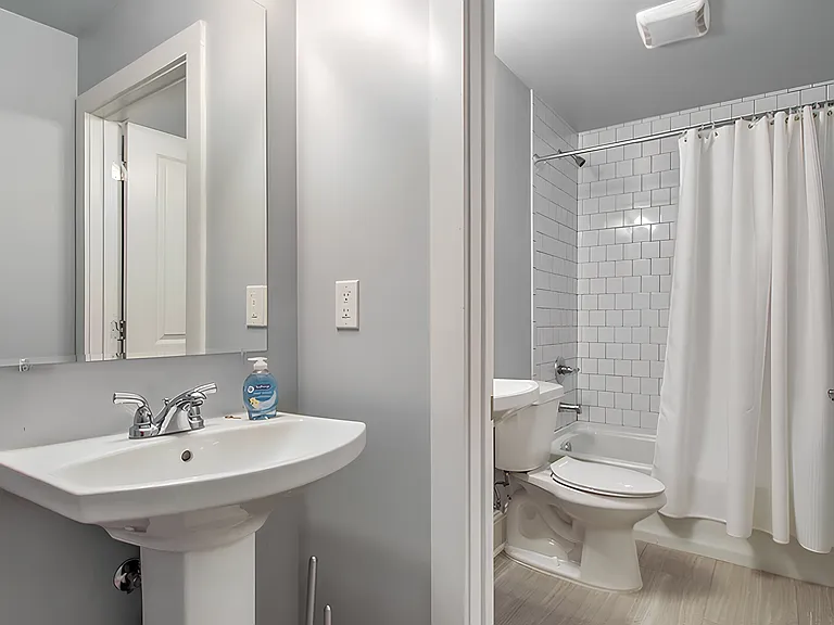 Brand new bathroom with and tile floor and walls. There is a second sink outside the bathroom.