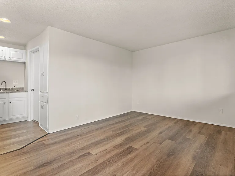 Spacious living area with modern wood-style flooring and a clean, neutral layout ready for your personal touch. Spacious living area with modern wood-style flooring and a clean, neutral layout ready for your personal touch.