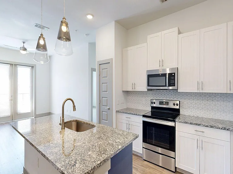 Apartment Kitchen with Stainless Steel Appliances, Dining and Living Room with Wood Style Flooring.