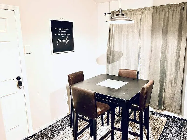 Dining area with a four-seat table, overhead pendant lighting, and full window coverage for added privacy.