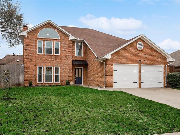 Traditional-style house with a chimney, an attached garage, brick siding, and driveway