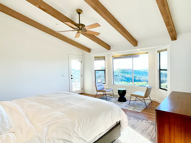 The primary bedroom features a king bed, high ceilings, and sweeping views