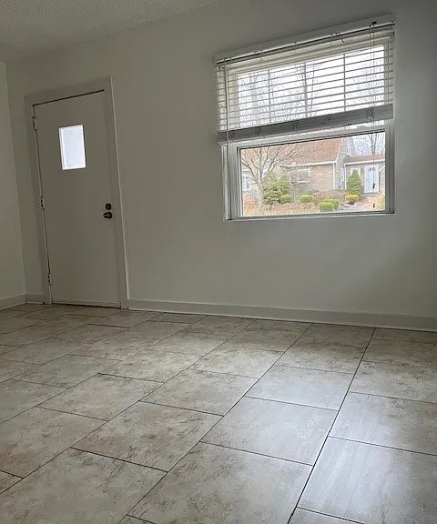 Living Room fitted with:
Large windows with private landscape views.
Front entry door (leads to front porch relaxation area with broom-finished concrete).