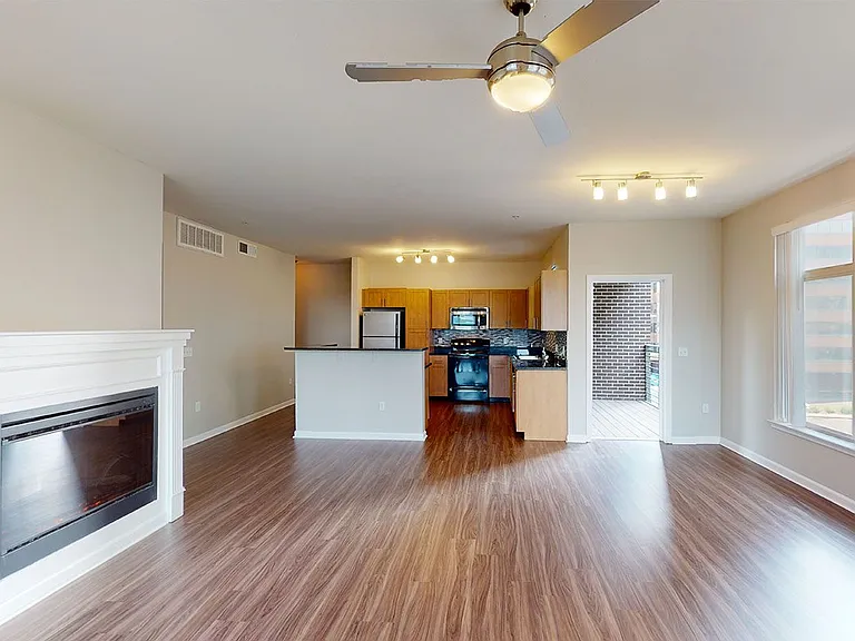 Apartment kitchen, dining and living room with wood-style flooring and fireplace in select homes.