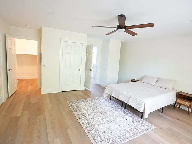 Spacious bedroom with wide-plank flooring, ceiling fan, large closet, and room for a full furniture setup.