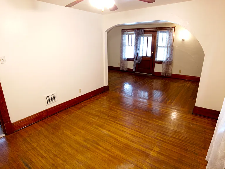 Dining room looking into the living room area. Original hardwood floor. Entrance to the porch/patio is through the door in the living room.