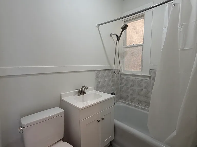 Bathroom with new vanity and toilet. Shower over tub.