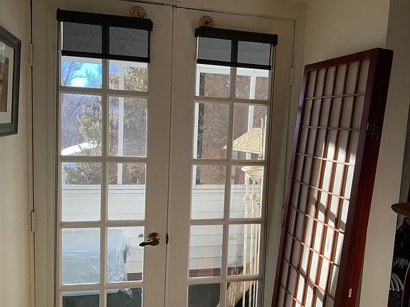 French doors in BDRM lead to a private 3 season inset balcony/ porch with lights,electrical outlets, lounge chair & bar table. with views of the mountains & 1.25 acre private property