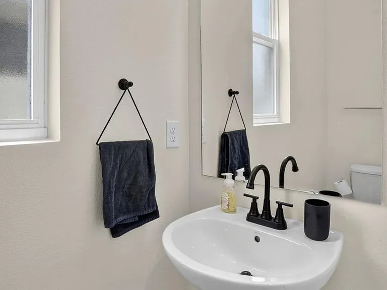 Half bath with pedestal sink, large wall mirror, and frosted window for natural light and privacy.