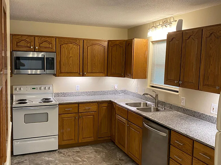 Kitchen with granite counters, oak cabinets, oven, microwave, and dishwasher.