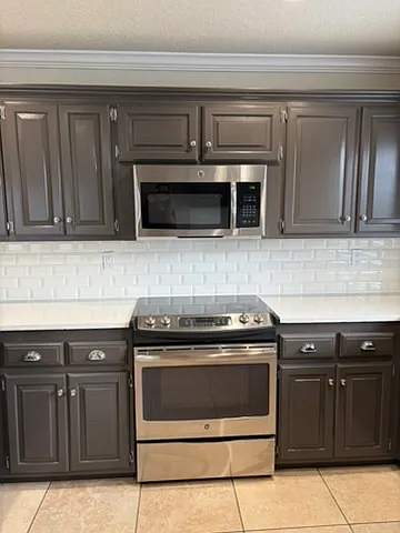 View of microwave, stove/oven, and cabinets in kitchen.