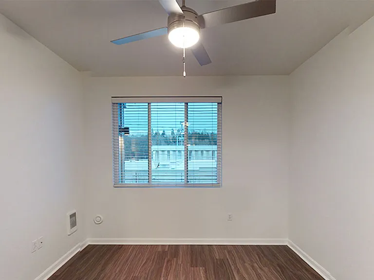 Spacious apartment bedroom with wood-style flooring.