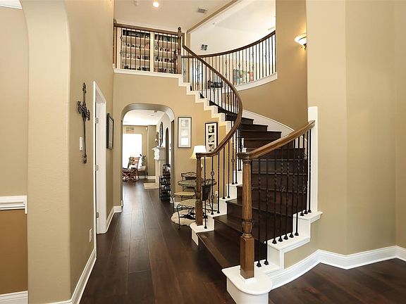 Simply Stunning! Terrific entryway with wood flooring, elegant paint palette, wrought iron stairway with wood risers/treads, and high ceilings with lots of natural lighting.