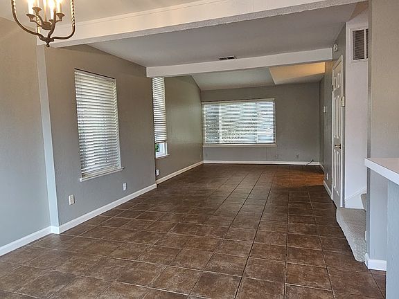 Spacious open living and dining area with tile flooring and large windows that fill the space with natural light. Clean lines and neutral tones create an inviting setting ready for any style.